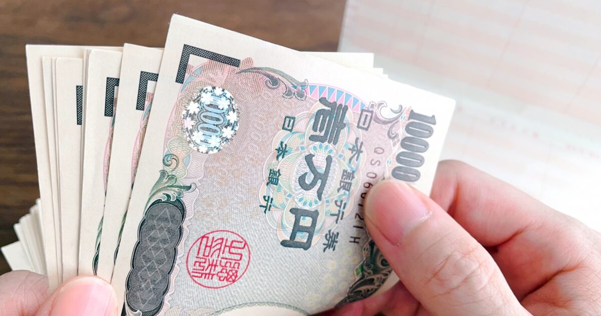 一万円札を数える手元と通帳